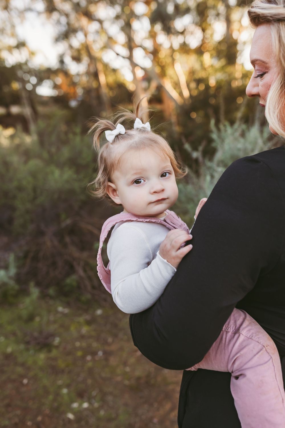 A tender moment captured between parent and child in soft golden light against a natural outdoor backdrop.