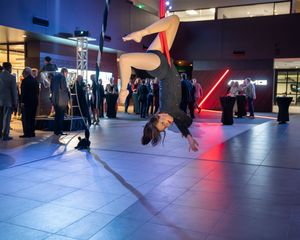 Dance performance on illuminated blue floor with red accent lighting and audience silhouettes.