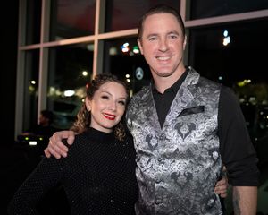 People pose together at an event wearing formal attire including a sparkly silver vest.