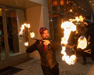 Fire performers create dramatic display with flaming torches in outdoor evening venue.