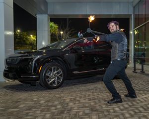 Night performance with fire twirling outside a luxury car showroom with brick pavers.