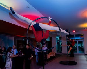 Performers practicing with illuminated props in a dimly lit indoor space with colorful lighting.