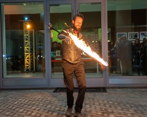 A series of nighttime photos showing a fire performer spinning flames in front of a building.