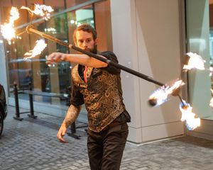 Fire dancers performing with flaming batons in an outdoor venue at night.
