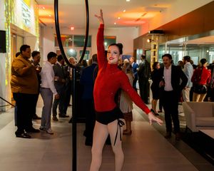 Performers practicing in a modern venue with red lighting and mirrored walls.