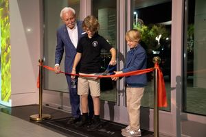 Ribbon cutting ceremony with participants at building entrance.