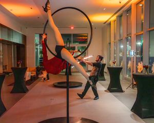 Aerial performer in red costume demonstrates acrobatic skills on suspended hoop apparatus.