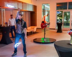 Performer doing fire tricks in an illuminated indoor space with orange lighting.