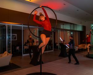 Performers demonstrate acrobatic moves in a dimly lit indoor space with red lighting.