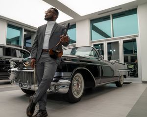 Classic vintage cars on display in a modern showroom with white columns and reflective floors.