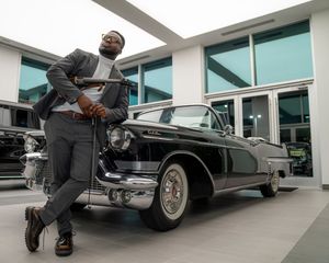 Classic vintage Cadillac car displayed in a modern building with glass windows.