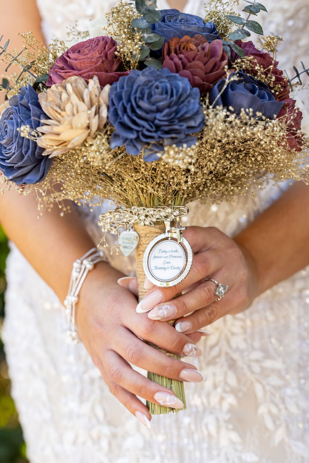 A wedding bouquet featuring blue and cream roses with gold accents and baby's breath.