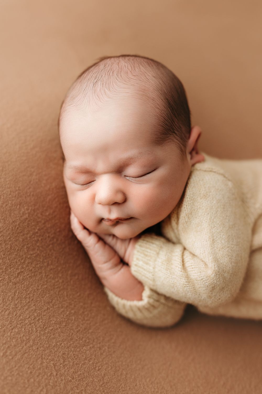 Peaceful sleeping newborn in cream wrap photographed in artistic side-by-side sequence on brown background.