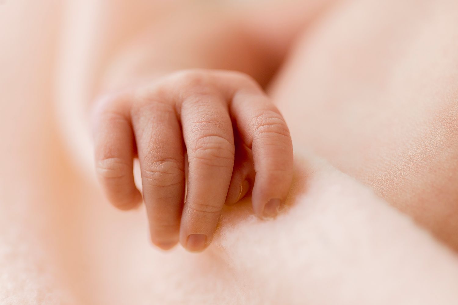 A peaceful sleeping newborn wrapped in soft white blankets with closed eyes and serene expression.