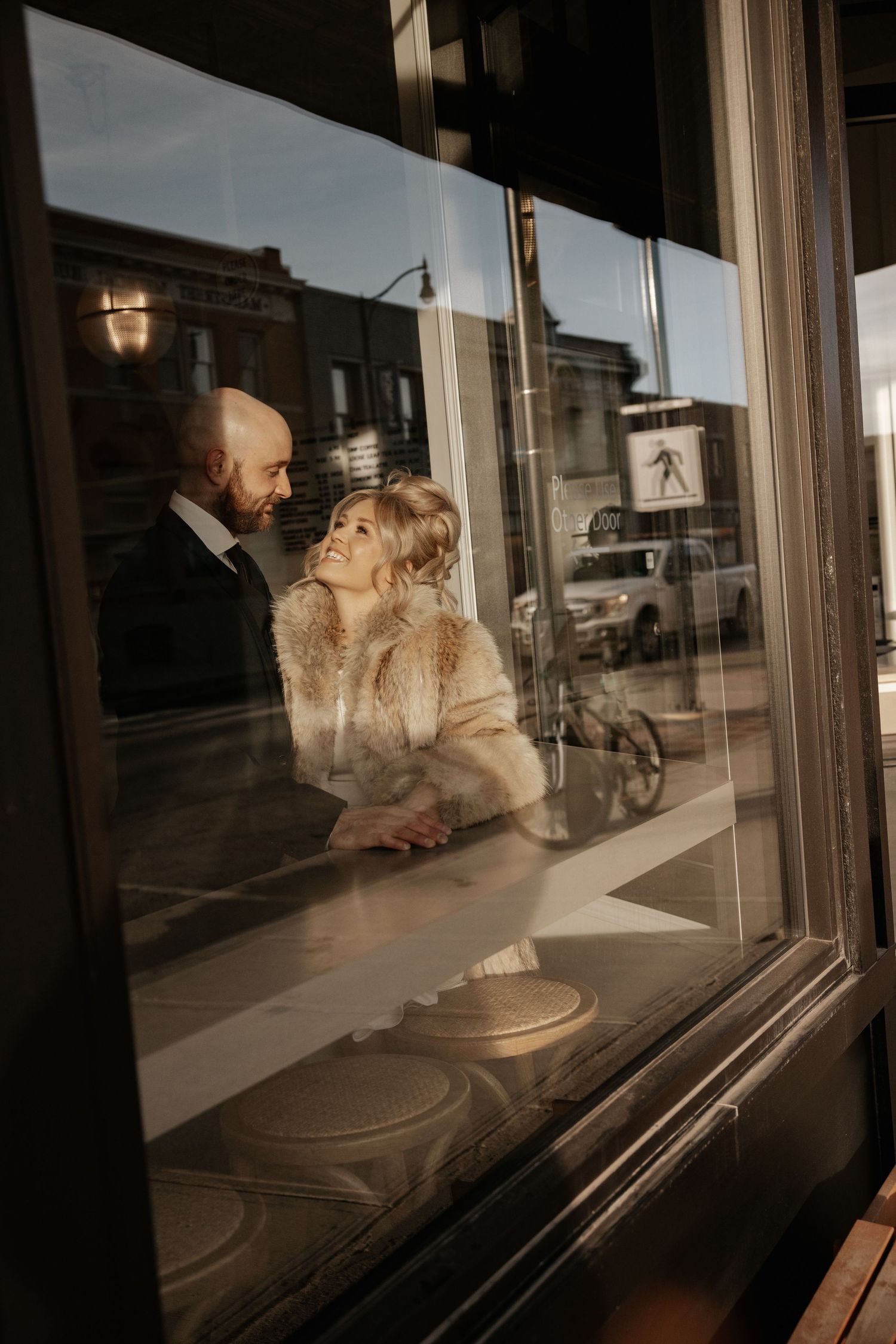 A series of five photos showing a couple in warm light posing through a window reflection at sunset.