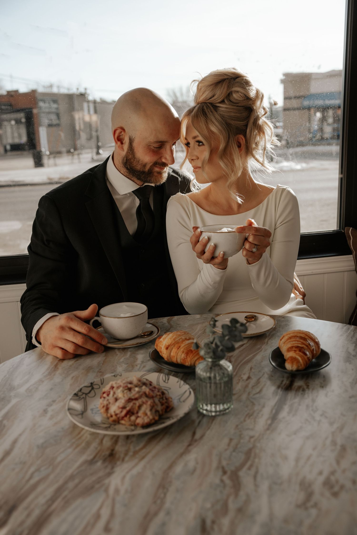A couple shares an intimate moment over breakfast at a marble table in a minimalist dining setting.