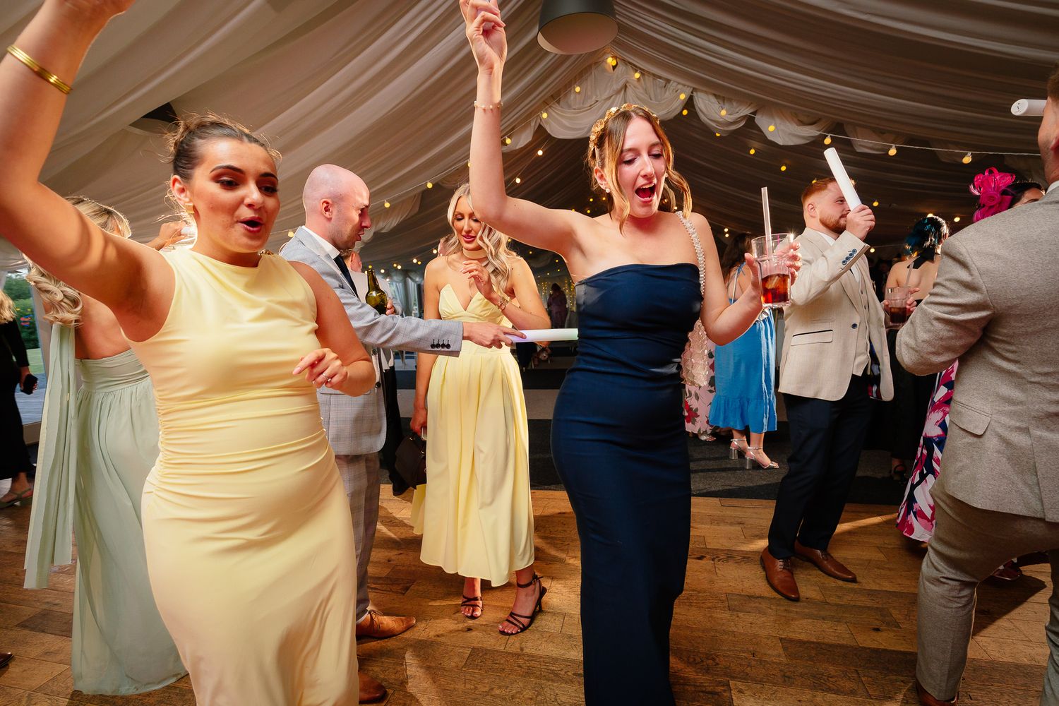 Wedding guests dance and celebrate together on the dance floor during a lively reception party.
