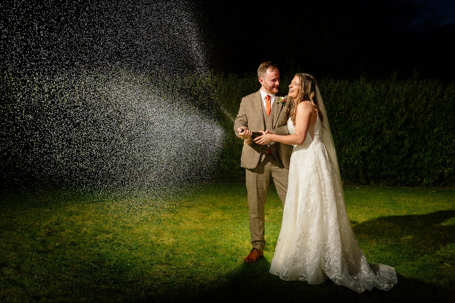 A romantic couple in wedding attire shares a tender moment during their nighttime outdoor photo session.