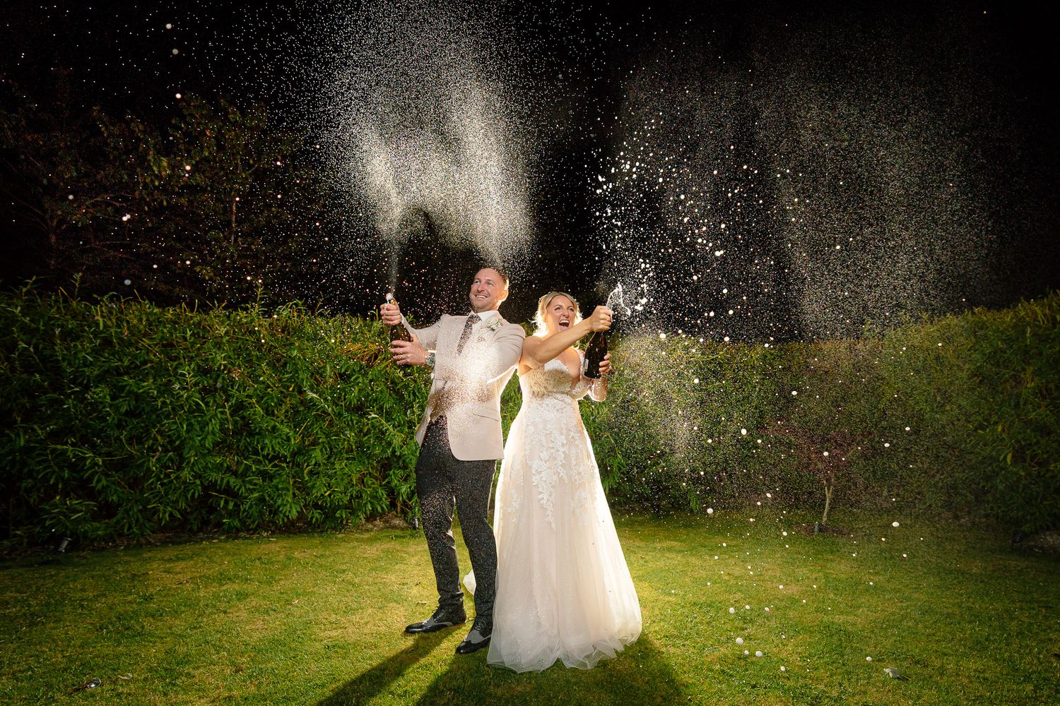 Newlyweds dance together in a garden while confetti sparkles around them in romantic evening light.
