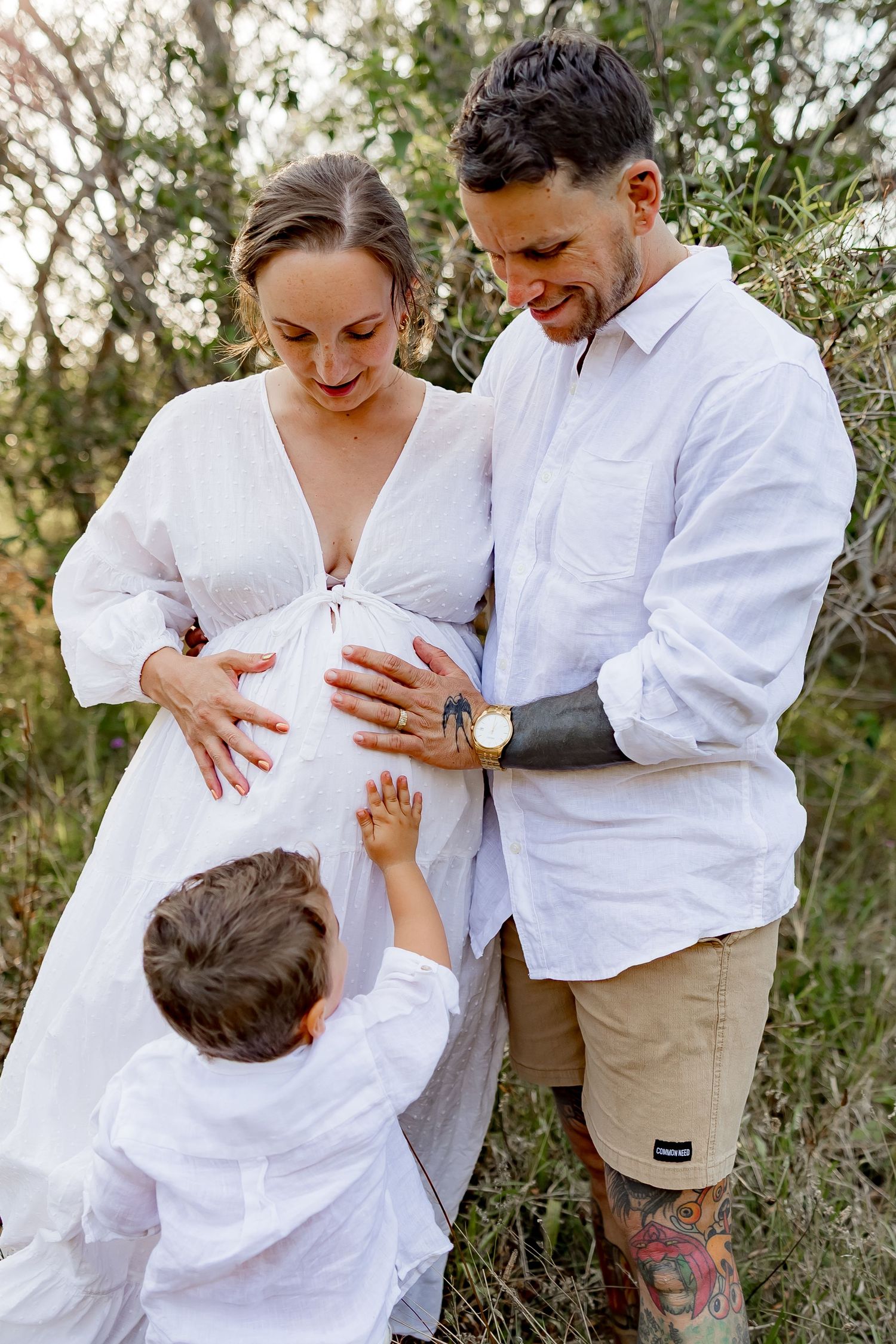 Family in white clothing shares tender moments together in a series of outdoor portraits.