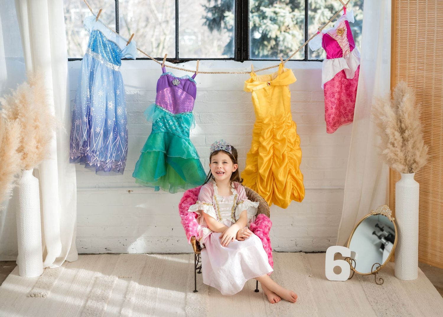 Colorful princess dresses and tutus hang on display in a bright retail space with white walls and natural lighting.