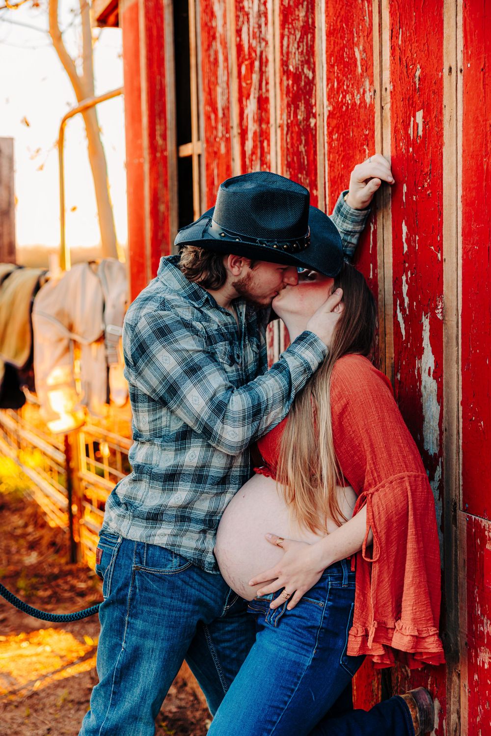 Romantic country engagement photos against a rustic red barn during golden hour.
