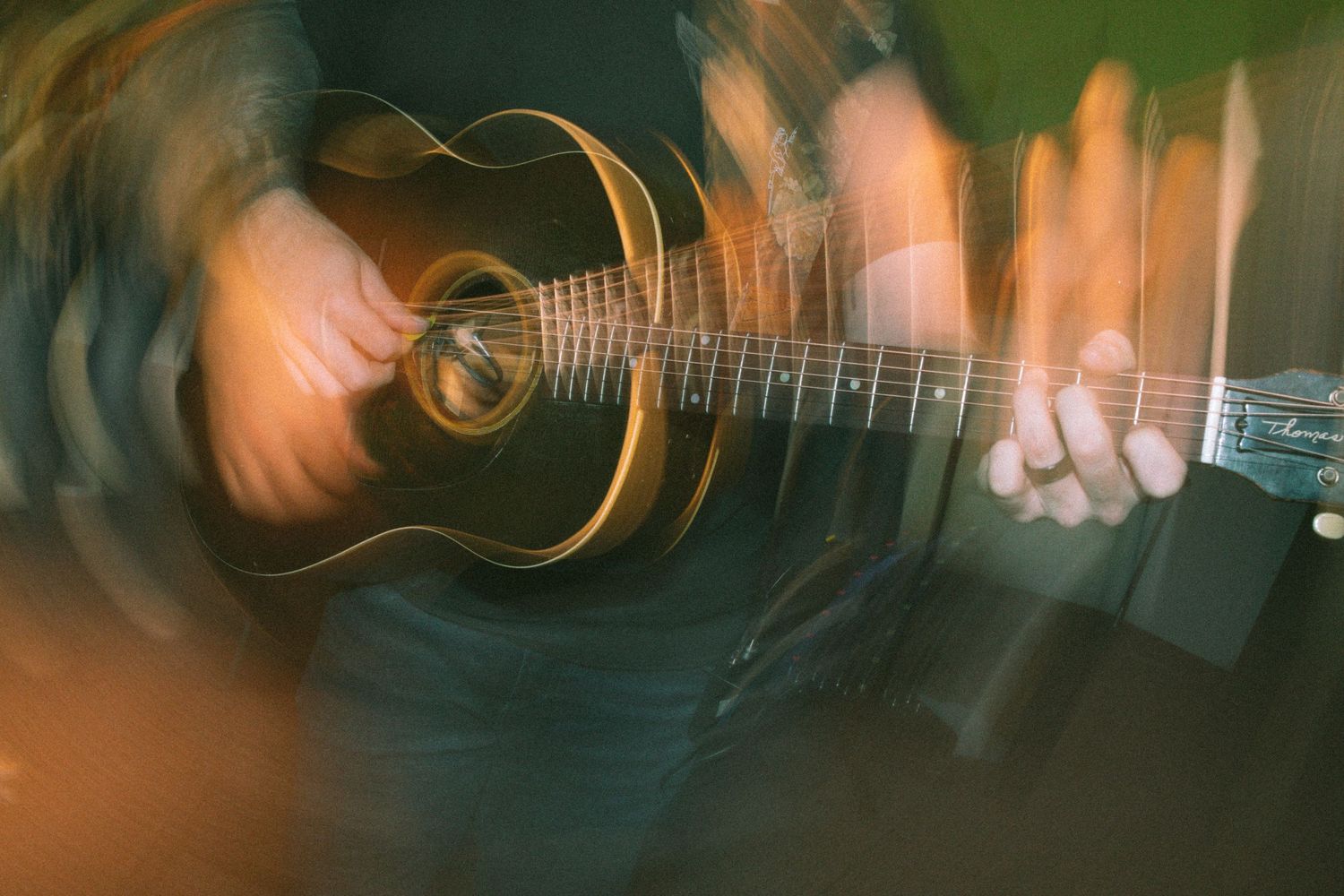 Motion blur artistic photo of hands playing an acoustic guitar at a church worship service.