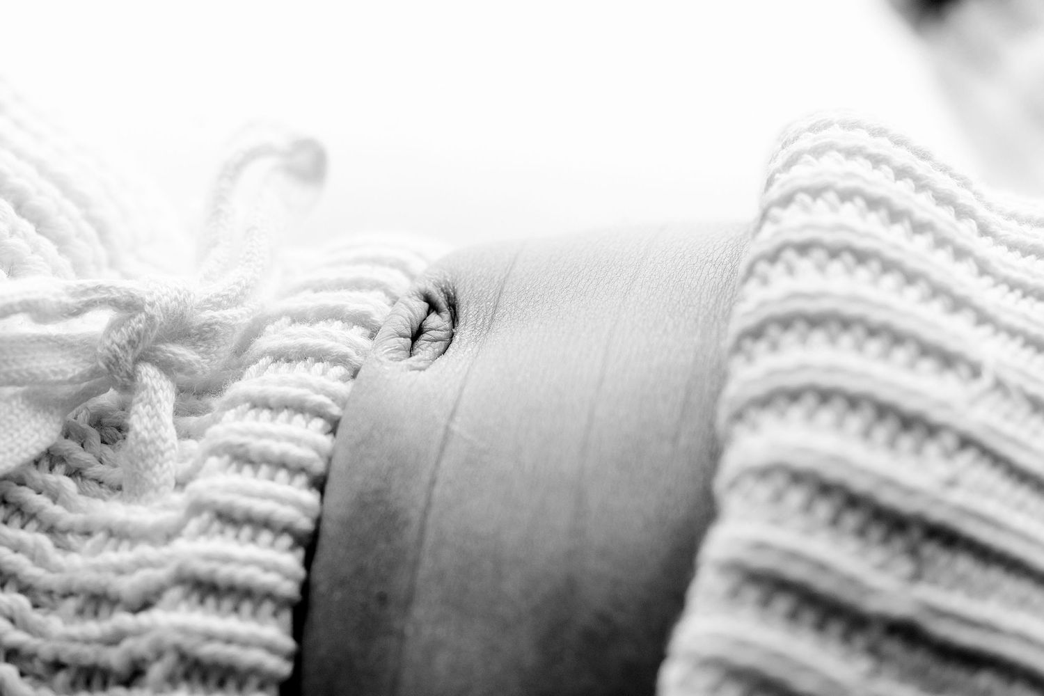 A black and white macro photograph shows a close-up view between cozy knit sweater folds.