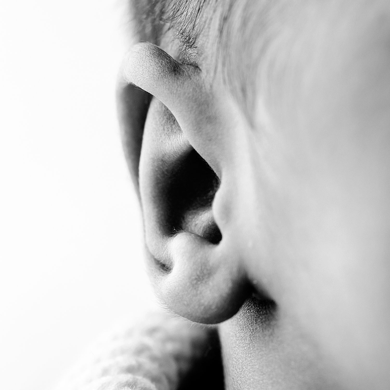Close-up profile view of a nose and lips against a light background in black and white.