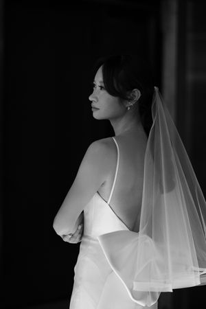 Black and white portrait of a bride in a strapless gown with flowing veil.