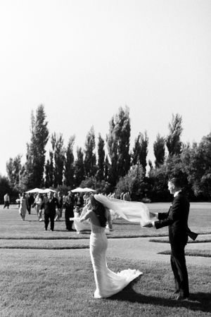 Couple celebrating on lawn with tall poplar trees in background.