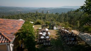 Scenic aerial view of an outdoor wedding ceremony setup with mountain vistas.