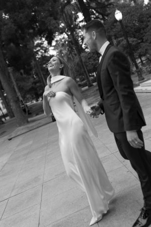 Black and white photo of a couple sharing a joyful moment in elegant wedding attire.