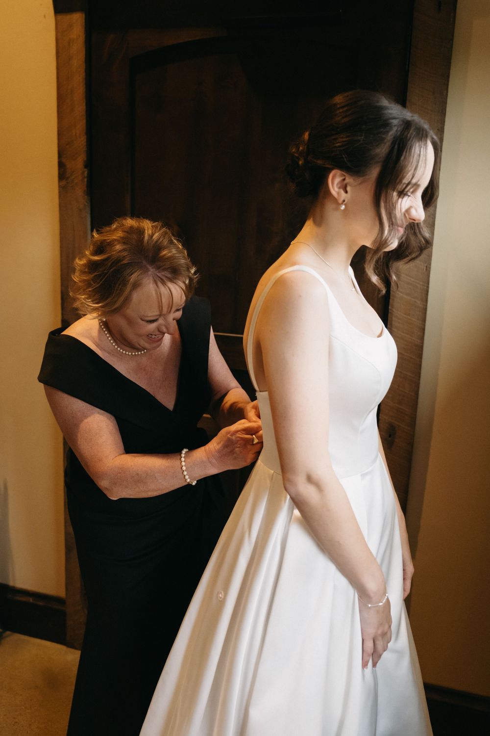 A series of photos showing the delicate process of adjusting and fitting a flowing white wedding dress.