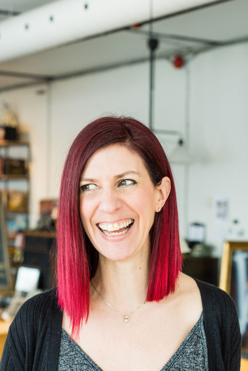 A vibrant portrait showing bright red hair and joyful expression in an indoor setting.