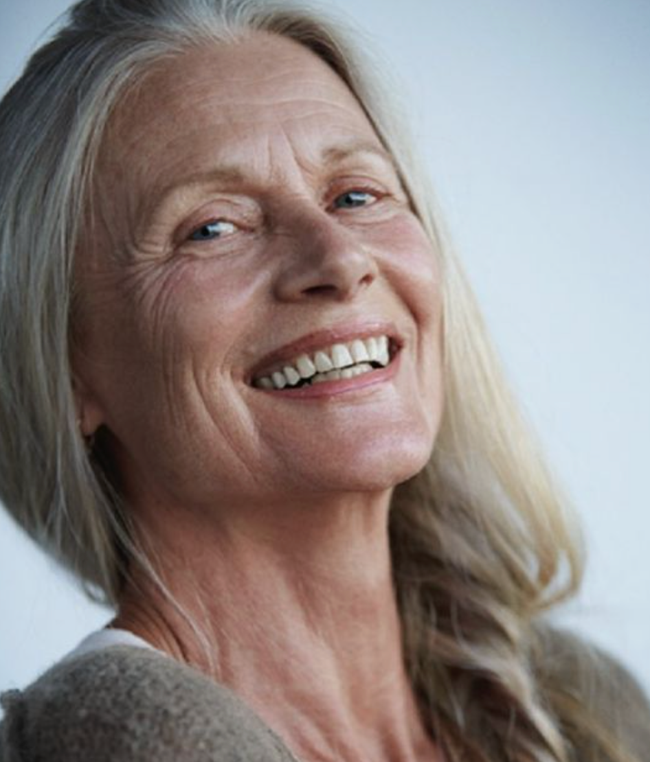 Portrait of mature woman with long silver hair smiling warmly.