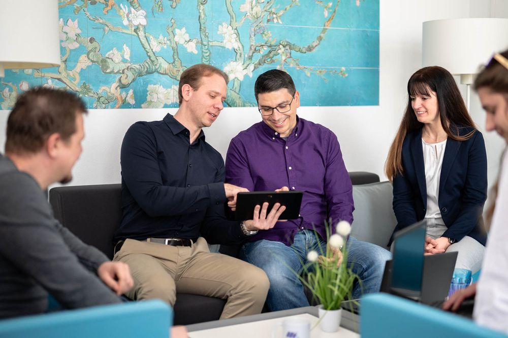 Business team collaborating and reviewing documents together in modern office with turquoise wall art.
