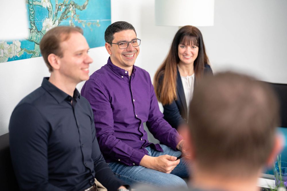 A group of people sitting at a conference table having a business discussion in a modern office setting.