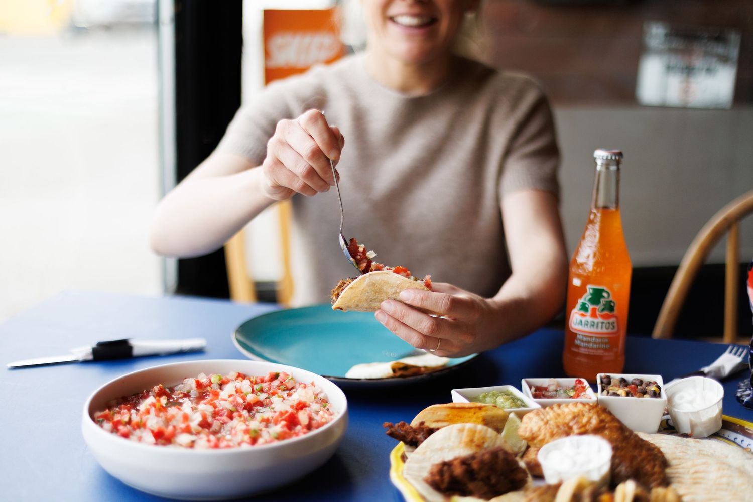 Friends sharing a meal together at a restaurant table with various dishes and drinks spread out.