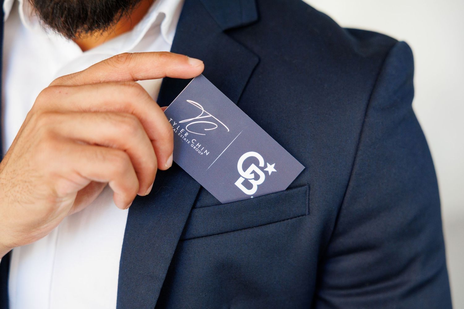 Professional in a navy suit jacket removes a gray price tag from the sleeve in closeup view.