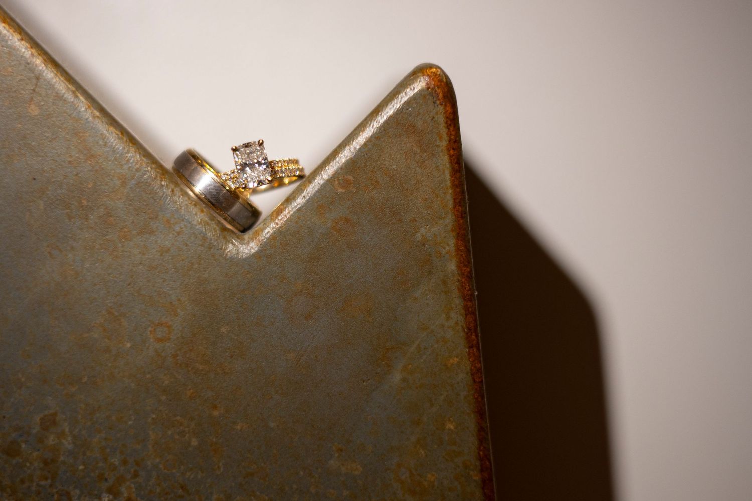 Close-up of a diamond and gold engagement ring and two wedding rings.