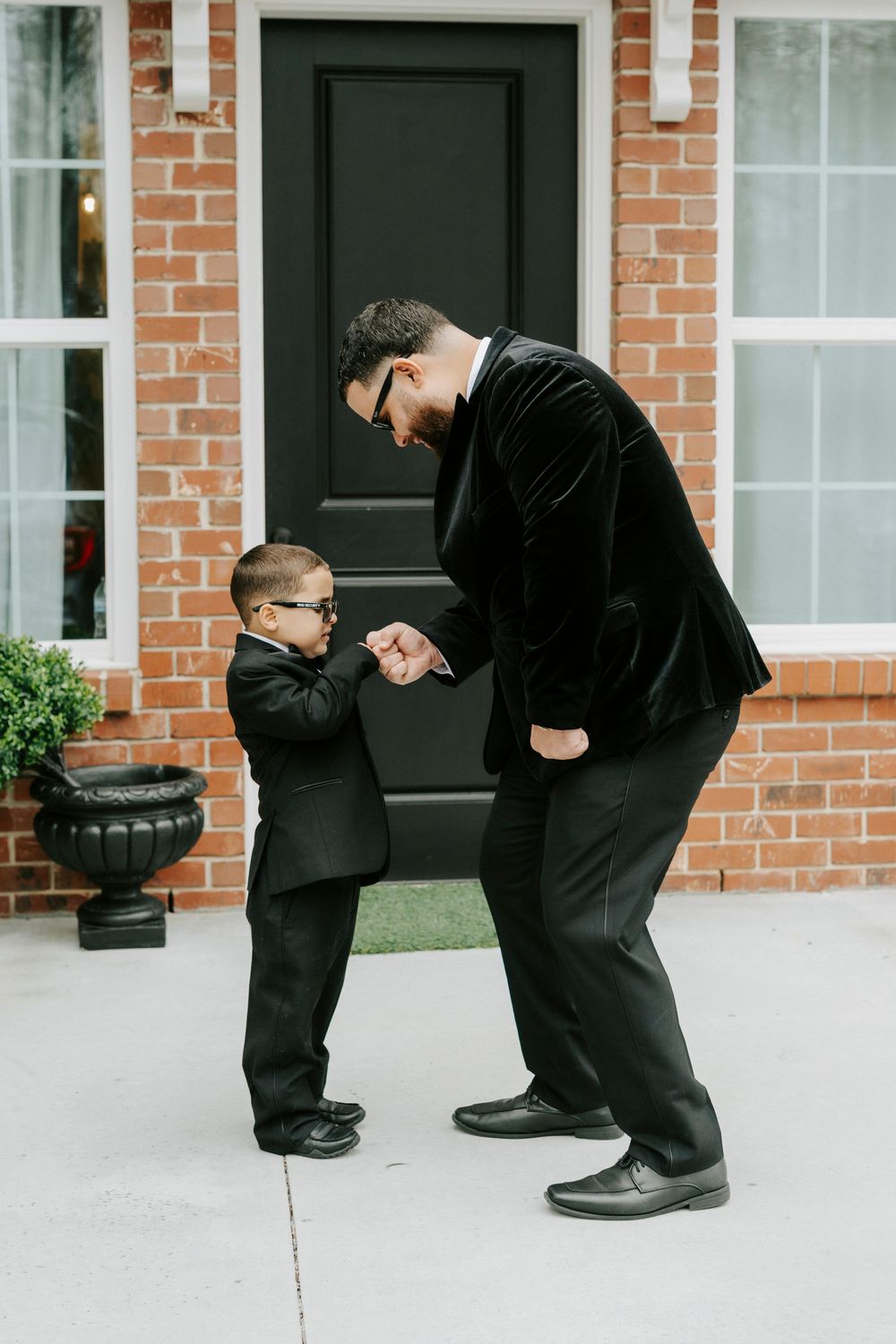 Sequence of formal dress shoes being tied in front of a brick building entrance.