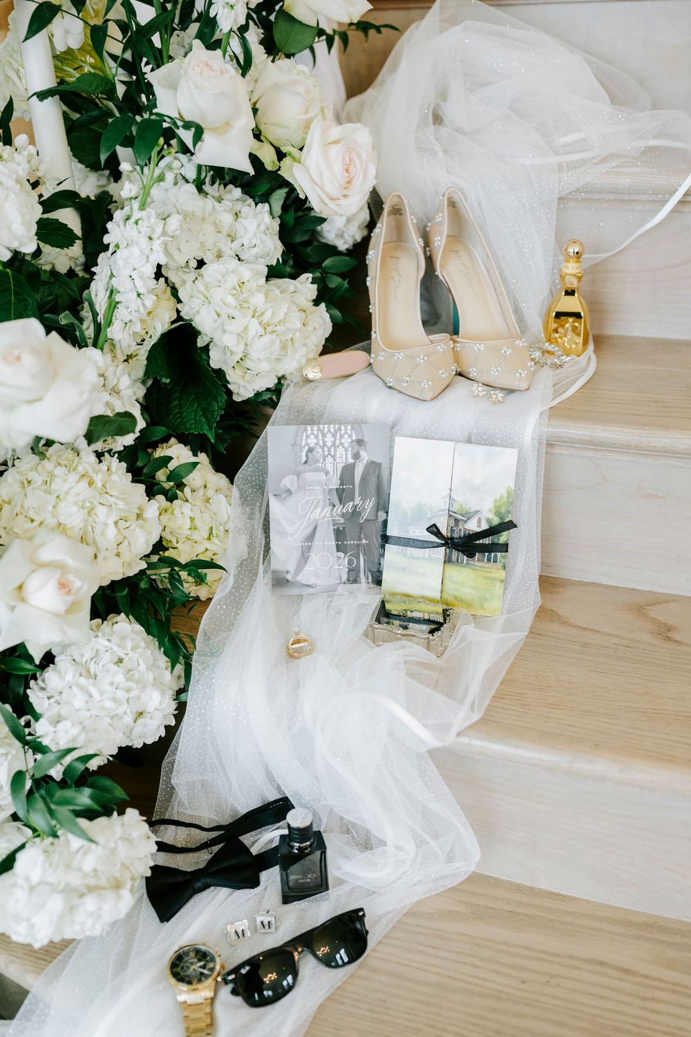 White floral arrangements with hydrangeas and roses decorate wooden steps at an elegant wedding venue.