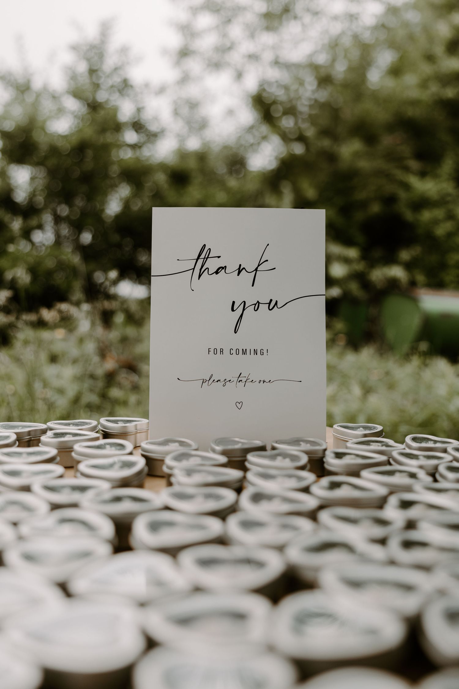 Elegant wedding thank you sign displayed among rows of small wooden guest favor containers.