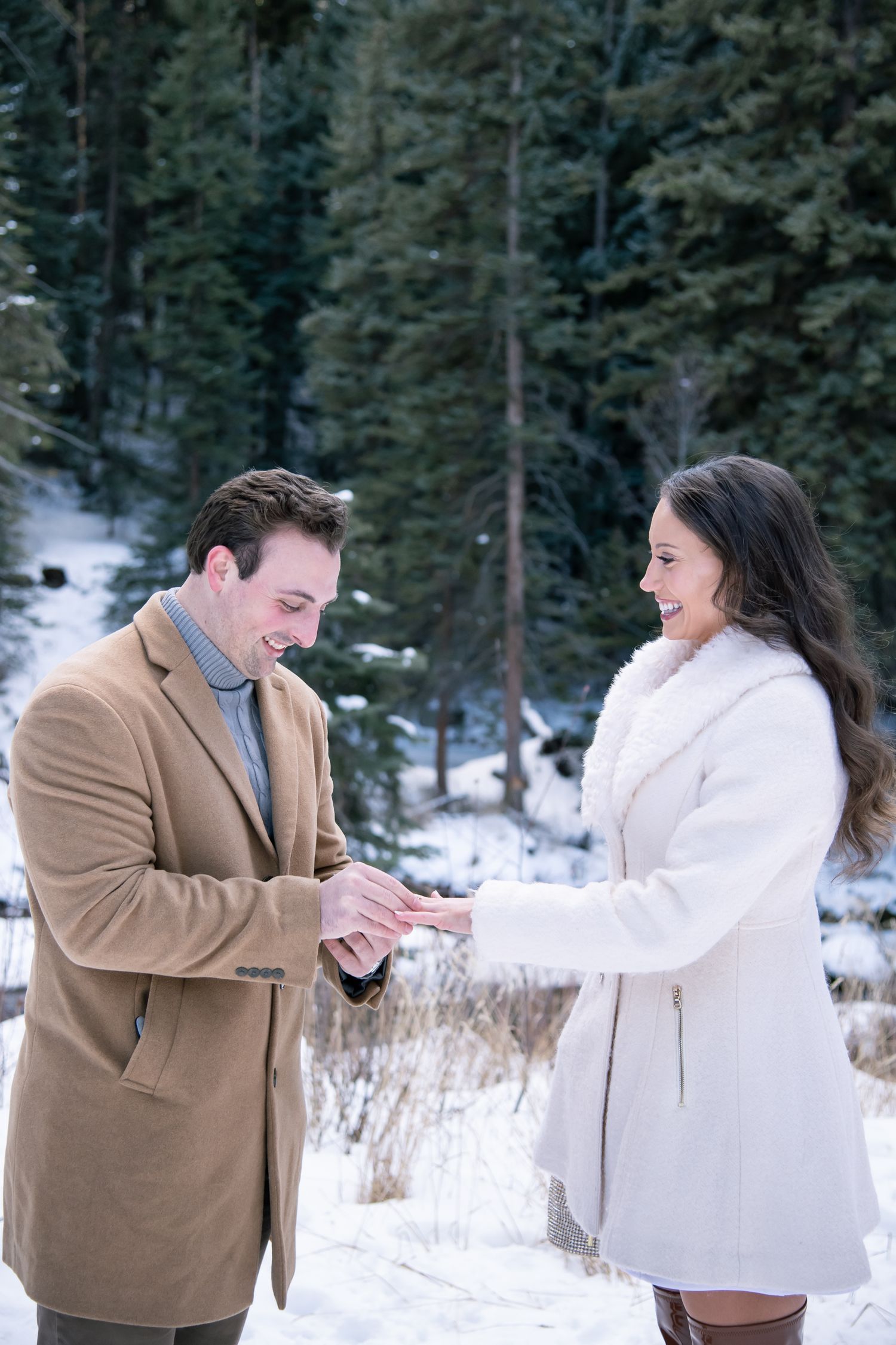 Vail Colorado engagement in the winter as a man slides a new engagement ring onto his new fiancé's finger