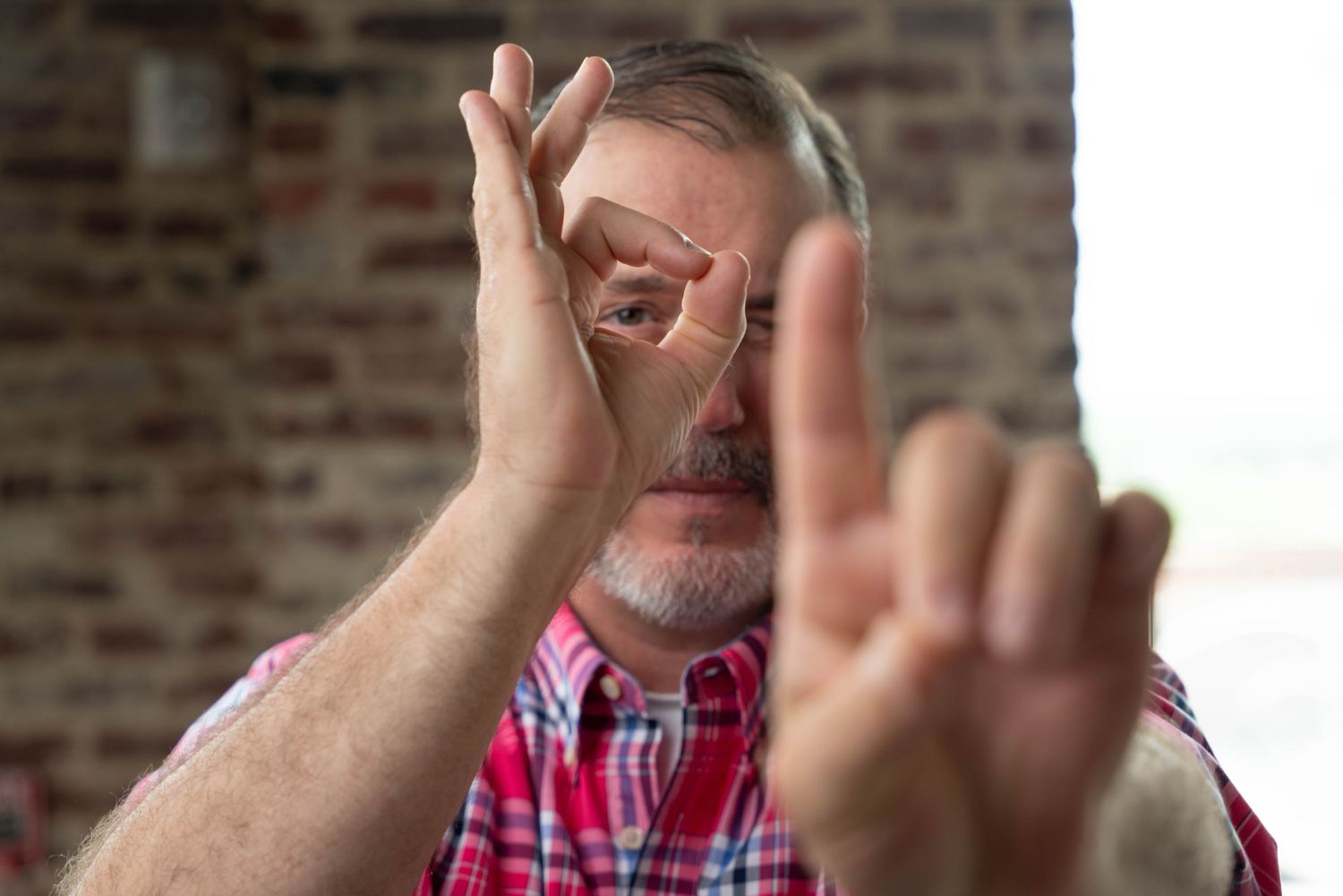 Portrait of a main aiming through is fingers