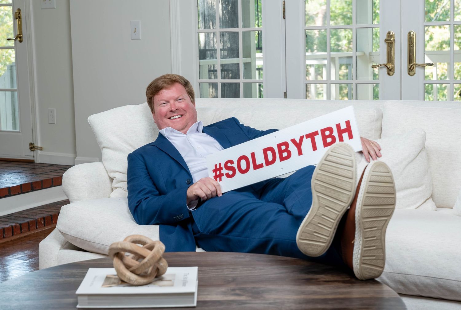 funny headshot. Man laying on couch holding branding banner
