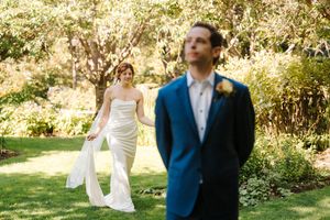 A couple in wedding attire walks through a sunlit garden path during an outdoor autumn wedding celebration.