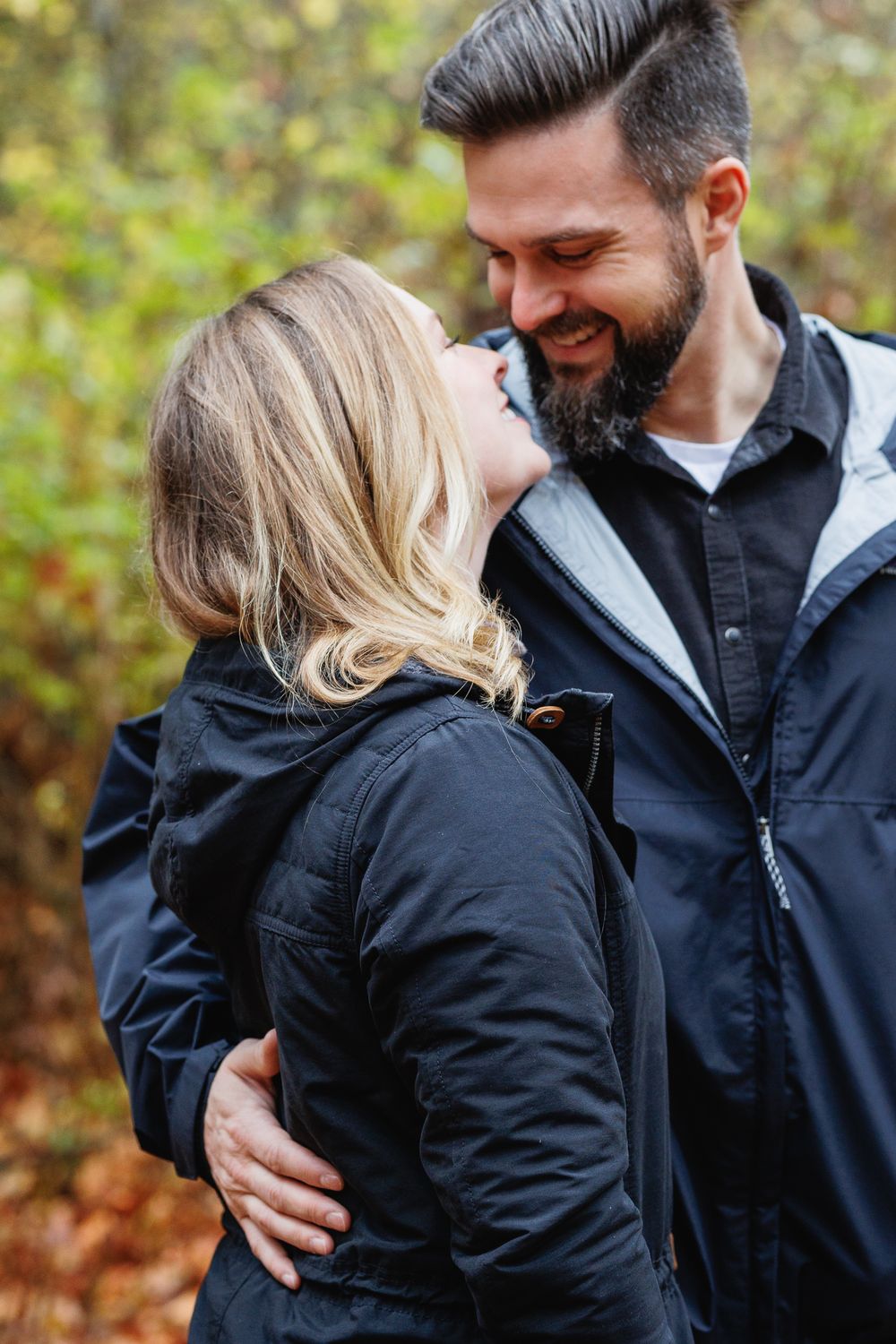 Happy couple embracing and smiling at each other in fall woodland.