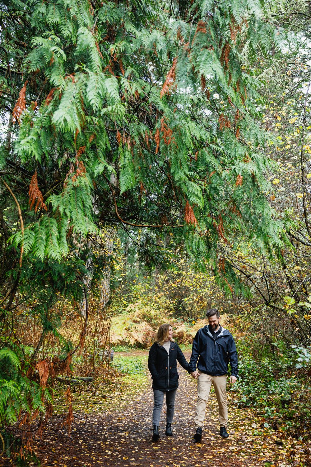Man and woman strolling hand in hand on autumn woodland trail.